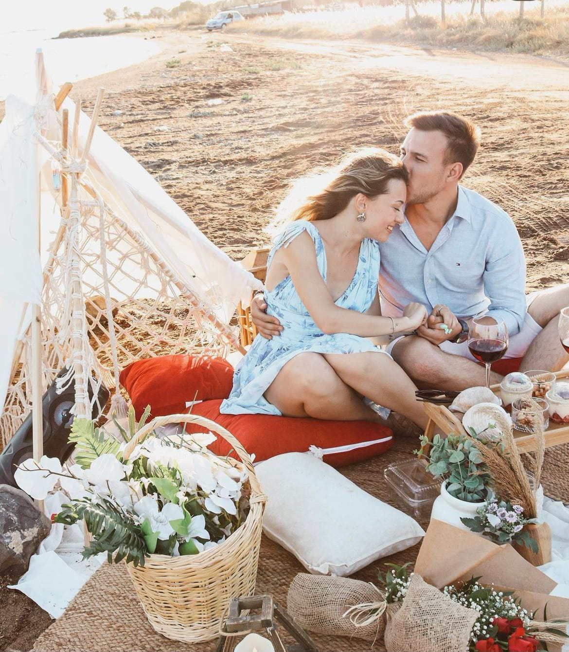 Plajda piknik sepetleriyle oturan bir çift.